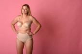 attraktive mollige Mädchen in Unterwäsche auf rosa Hintergrund