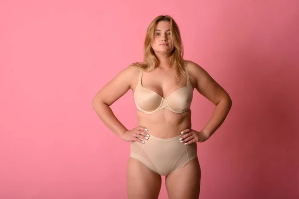 Привлекательная толстушка в нижнем белье на розовом фоне — стоковое фото