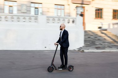 Cityscape arka planda bir tekme scooter sürme çekici iş adamı