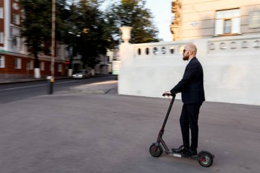 Cityscape arka planda bir tekme scooter sürme çekici iş adamı