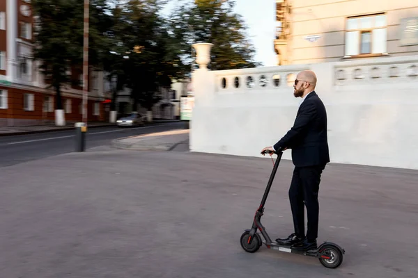 Vonzó üzletember lovaglás kick robogó a városkép háttérben — Stock Fotó