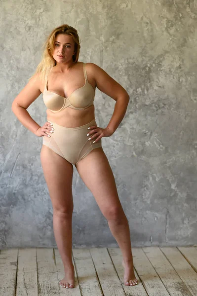 Hermosa mujer con sobrepeso en traje de baño beige sobre fondo gris —  Fotos de Stock