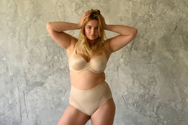 Hermosa mujer con sobrepeso en traje de baño beige sobre fondo gris —  Fotos de Stock