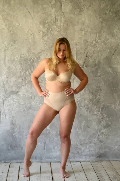 Bella donna in sovrappeso in costume da bagno beige su sfondo grigio — Foto Stock