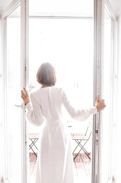 Menina de vestido branco abre a porta para a varanda. dia do casamento — Fotografia de Stock