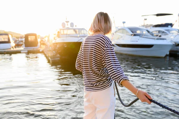 kız denizci demirlemiş yat için deniz ipi çeker. Deniz tarzı giysiler