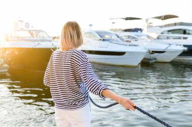 kız denizci demirlemiş yat için deniz ipi çeker. Deniz tarzı giysiler