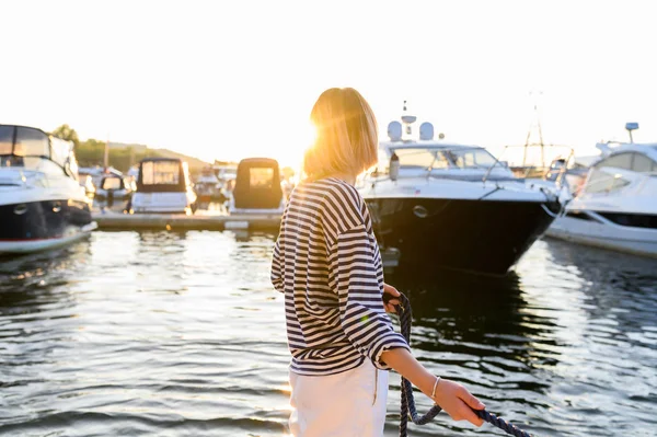 Genç deniz tarzı kadın teknede oturuyor ve ileriye dönük