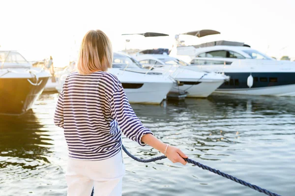 Genç deniz tarzı kadın teknede oturuyor ve ileriye dönük