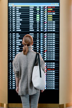 Havaalanında uçuş çetele karşı duran genç kadın