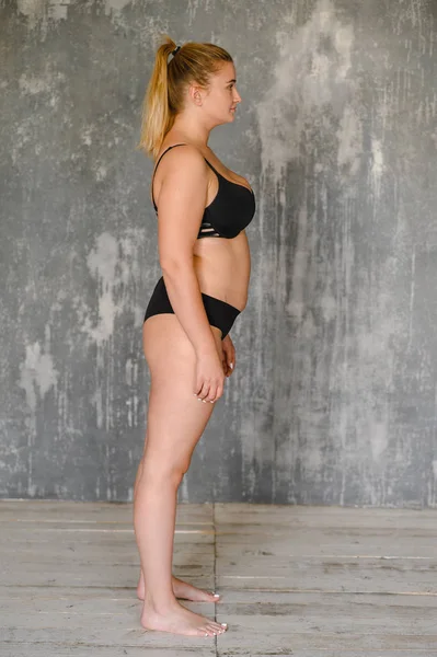 Una ragazza grassoccia in costume da bagno si trova vicino al muro. Corpo positivo. Dimensione più — Foto Stock