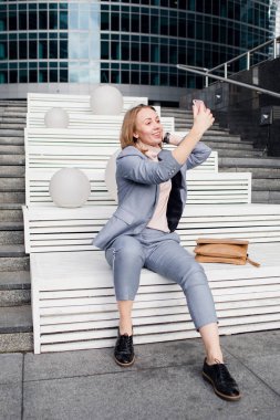 Güzel genç bir kadın akıllı telefonuyla selfie çekiyor.