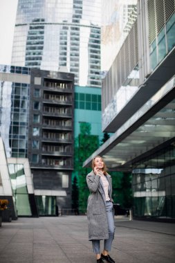 İş kadını bir ofis binasının arka planında telefonla konuşuyor.