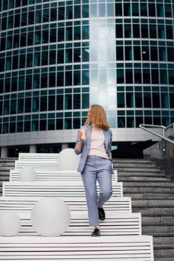 İş elbisesi giymiş olgun bir kadının eve telefonla konuşması. Şehir geçmişinde cep telefonu kullanan kıdemli bir iş kadını.