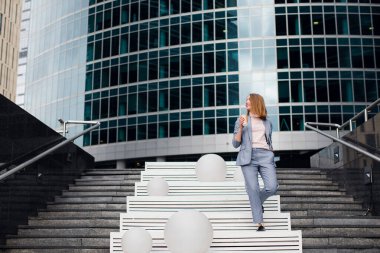 İş elbisesi giymiş olgun bir kadının eve telefonla konuşması. Şehir geçmişinde cep telefonu kullanan kıdemli bir iş kadını.