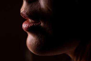 Siyah arka planda seksi dudakları olan genç bir kadın, yakın plan.