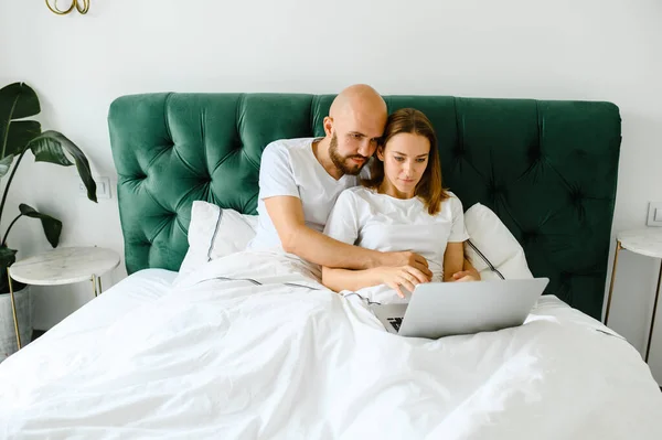 Jovem casal usando laptop juntos na cama — Fotografia de Stock