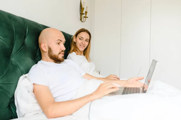 Jeune couple utilise un ordinateur portable au lit. matin freelance . — Photo