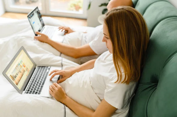 Νέοι άνθρωποι στο σπίτι ή χιλιετή όμορφο ζευγάρι στο ξενοδοχείο χρησιμοποιώντας σύνδεση στο internet και συσκευές τεχνολογίας, όπως φορητό υπολογιστή — Φωτογραφία Αρχείου