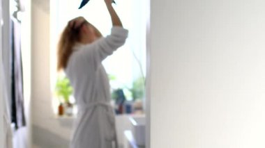 Genç ve güzel bir kız Bokeh 'te saç kurutma makinesiyle saç kurutuyor.