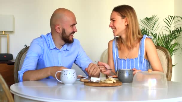 Счастливая пара дома завтракает. Счастливая женщина целует мужчину на частной кухне . — стоковое видео
