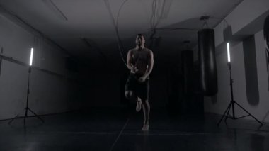 Erkek boksör spor salonunda sıkı çalışıyor. Adam eski bir spor salonunda ip kullanıyor, ısınıyor. Spor konsepti