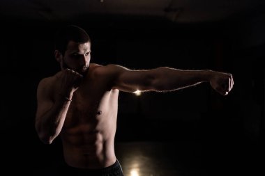 Erkek boksör boks ringinde gölge boksu yapıyor. Boksör bir boks stüdyosunda yumruk pratiği yapıyor. Siyah arkaplan