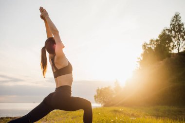 Parkta yoga yapan genç bir kadın. Vücut pozitif, açık hava sporları