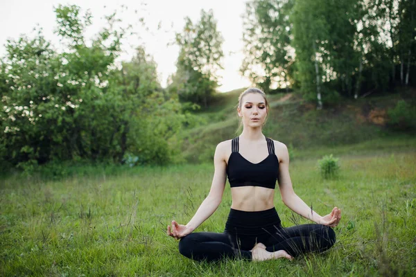 Retrato de jovem praticando ioga no jardim.felicidade feminina. fundo turvado.Estilo de vida saudável e conceito de relaxamento.Menina fazendo ioga no parque — Fotografia de Stock