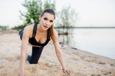 Kumsalda çalışan neşeli bir kız. Spor hocası egzersiz yapıyor.