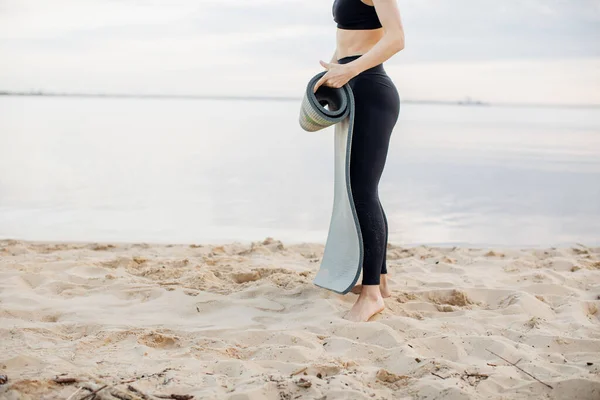 Sportmeisje doet yoga op het strand. Meisje met trainingsmat — Stockfoto