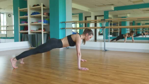 Jonge fit sportieve meisje in zwarte top, zwarte legging doet oefeningen. Sport- en fitnesstraining. Een gezonde levensstijl. strekken, naar voren leunen — Stockvideo