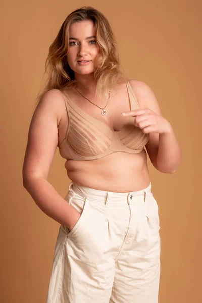 Indah kelebihan berat badan wanita dalam pakaian renang krem di latar belakang merah muda — Stok Foto