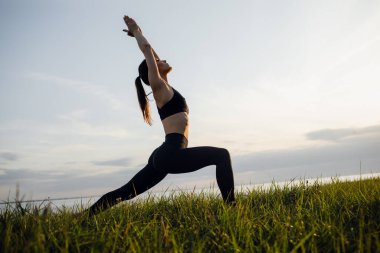 Sportif bir kız parkta yoga yapıyor. Açık hava sporları aktiviteleri