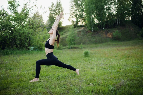 Ein sportliches Mädchen macht Yoga im Park. Sportliche Aktivitäten im Freien — Stockfoto