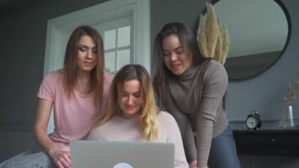 Three young women sit at home and make an order in an online store via a laptop — Stock Video