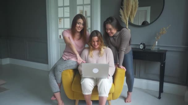 Три молодые женщины сидят дома и делают заказ в интернет-магазине через ноутбук — стоковое видео