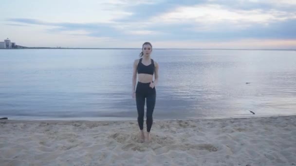 Modelo de fitness entra para los deportes en la playa. Hace ejercicios abdominales — Vídeo de stock