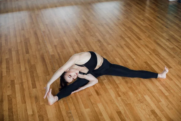 Schöne selbstbewusste Fitness-Girl in sportlicher Trainingskleidung macht Stretching Yoga-Übungen in ihrem Yoga-Studio — Stockfoto
