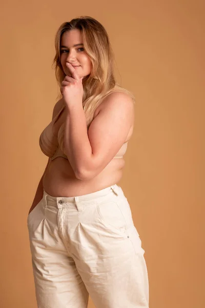 Hermosa mujer con sobrepeso en traje de baño beige sobre fondo rosa — Foto de Stock