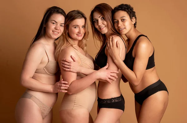 Amizade, beleza, corpo positivo e conceito de pessoas - grupo de mulheres felizes diferentes em roupas íntimas sobre fundo cinza — Fotografia de Stock