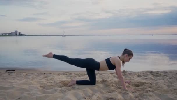 Jeune fille s'étend sur le bord de la mer au coucher du soleil. entraînement en plein air ou yoga — Video