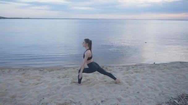 Jeune fille s'étend sur le bord de la mer au coucher du soleil. entraînement en plein air ou yoga — Video