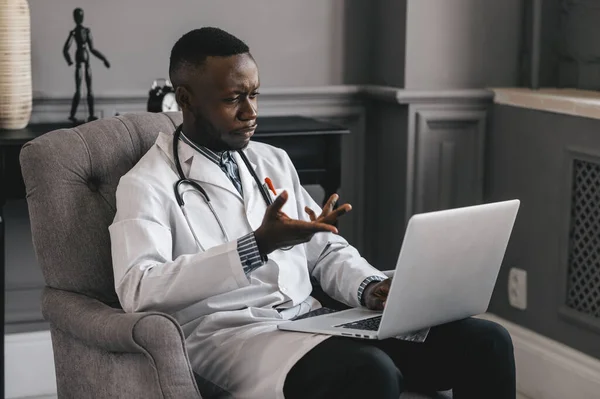 Czarny lekarz za pomocą laptopa do komunikacji z pacjentem. Uśmiechnięty mężczyzna Afrykański profesjonalny młody lekarz. — Zdjęcie stockowe