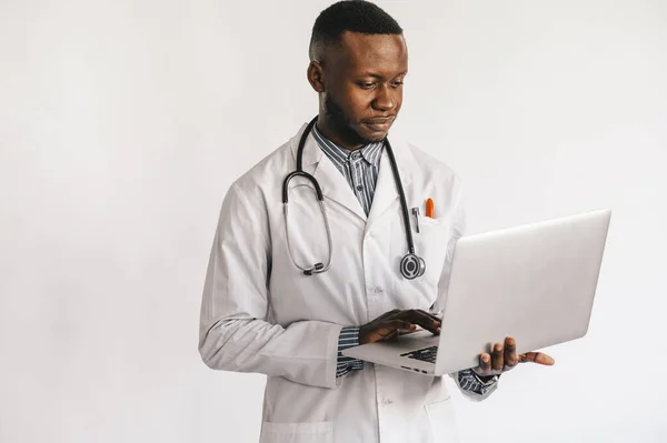 Czarny lekarz ze stetoskopem i laptopem na białym tle — Zdjęcie stockowe