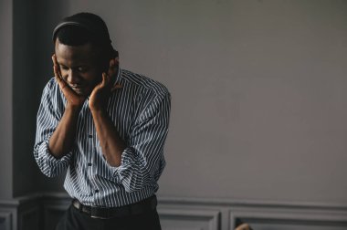 Genç Afrikalı adam kablosuz kulaklıkla müzik dinliyor ve evde dans ediyor.