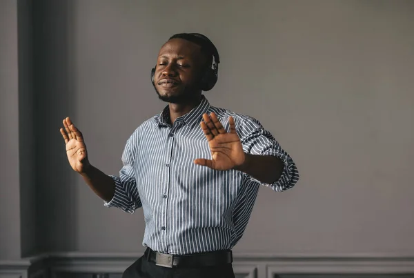 Jovem africano ouvindo música com fones de ouvido sem fio e dançando em casa — Fotografia de Stock