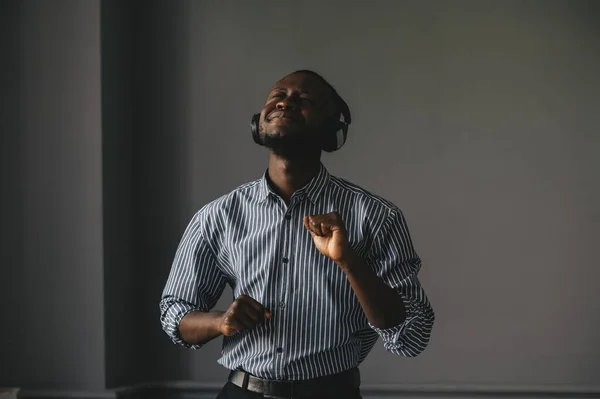 若いアフリカの男は、ワイヤレスイヤフォンで音楽を聴き、自宅で踊ります — ストック写真