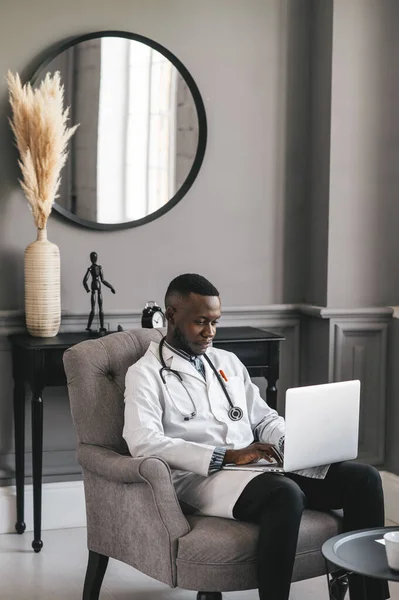 Szczęśliwy pozytywny czarny lekarz rozmawiać na wideo rozmowy z pacjentem, uśmiechnięty african amerykański człowiek pracownik mieć rozmowę online na laptopie — Zdjęcie stockowe