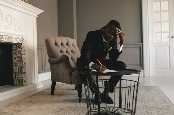 Jovem empresário afro-americano em terno de negócios tomando notas — Fotografia de Stock